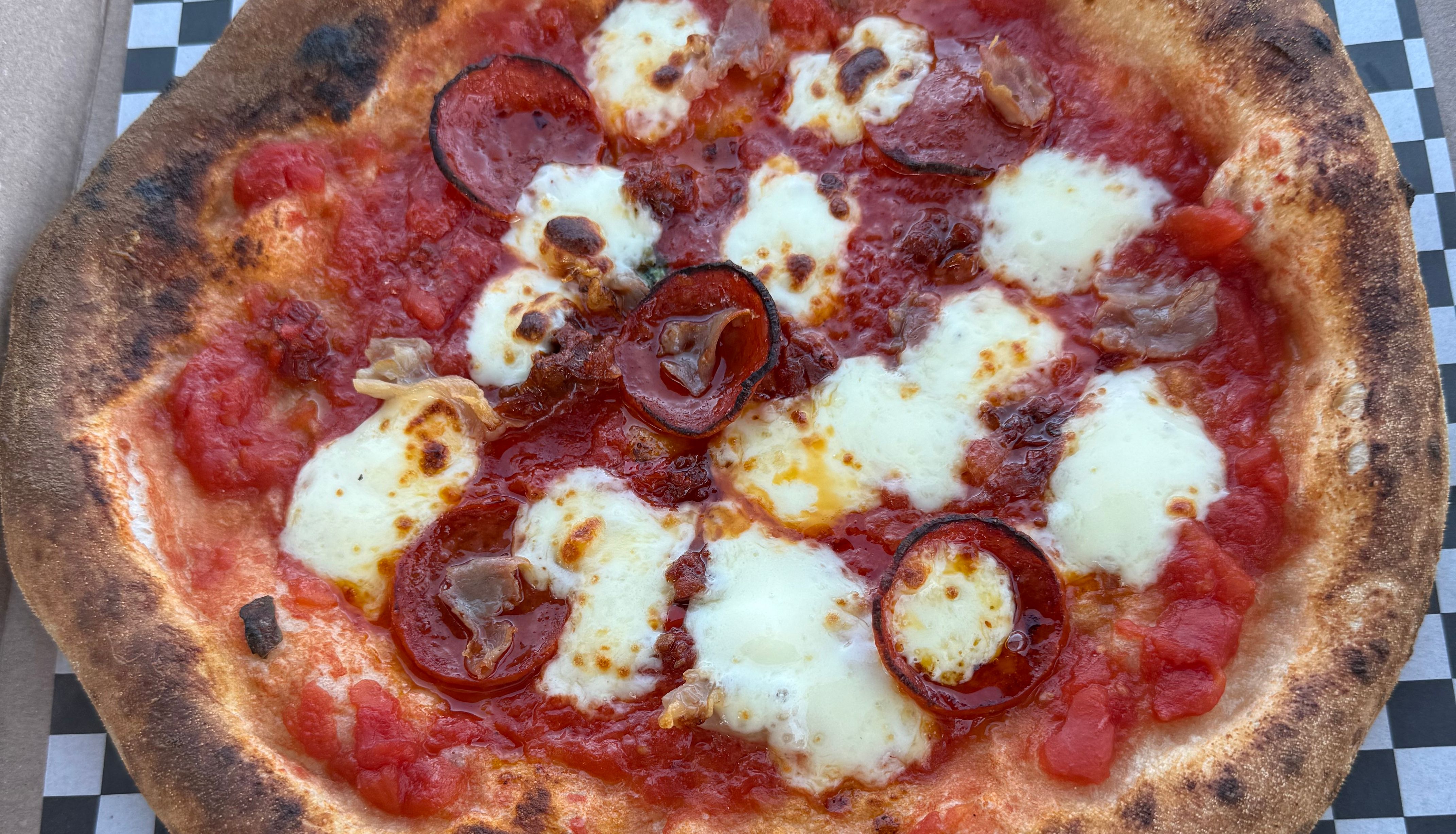 A cooked pizza with pepperoni, cheese, and tomato sauce in a pizza box