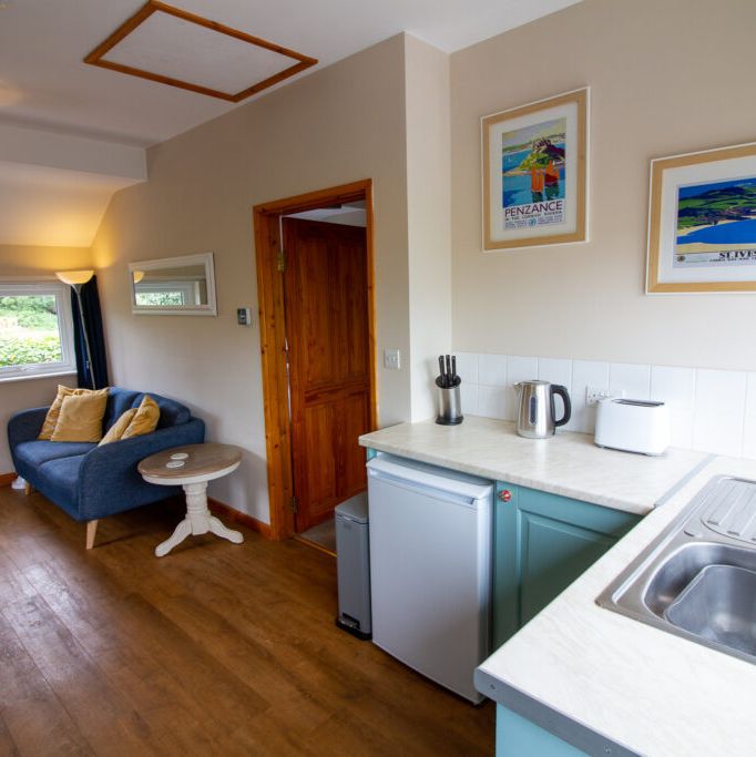 Bright and cozy studio kitchen and living area with a blue loveseat and kitchenette