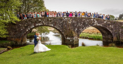Maggie McCall - bride and groom outside with guests on bridge