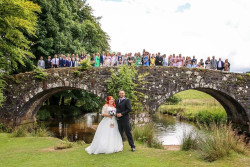 Lauren Spinks - bride and groom outside with guests on bridge