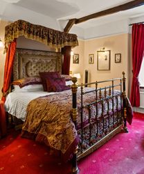 Luxurious vintage hotel room with four-poster bed, ornate fabrics, and traditional decor