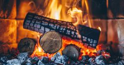 Close-up of burning logs in a fireplace with bright flames and glowing embers