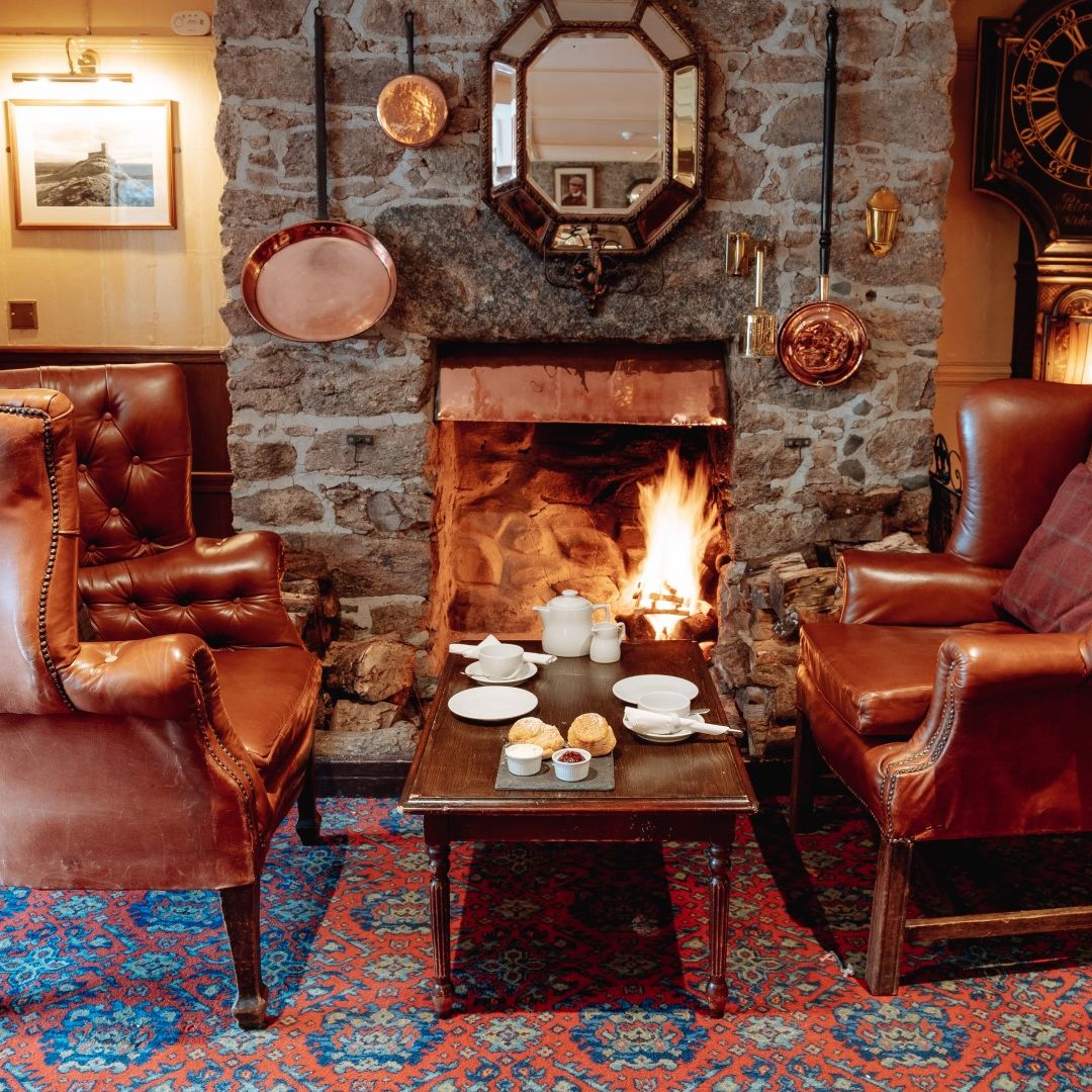Cozy lounge with leather chairs by a fireplace and tea set on a table