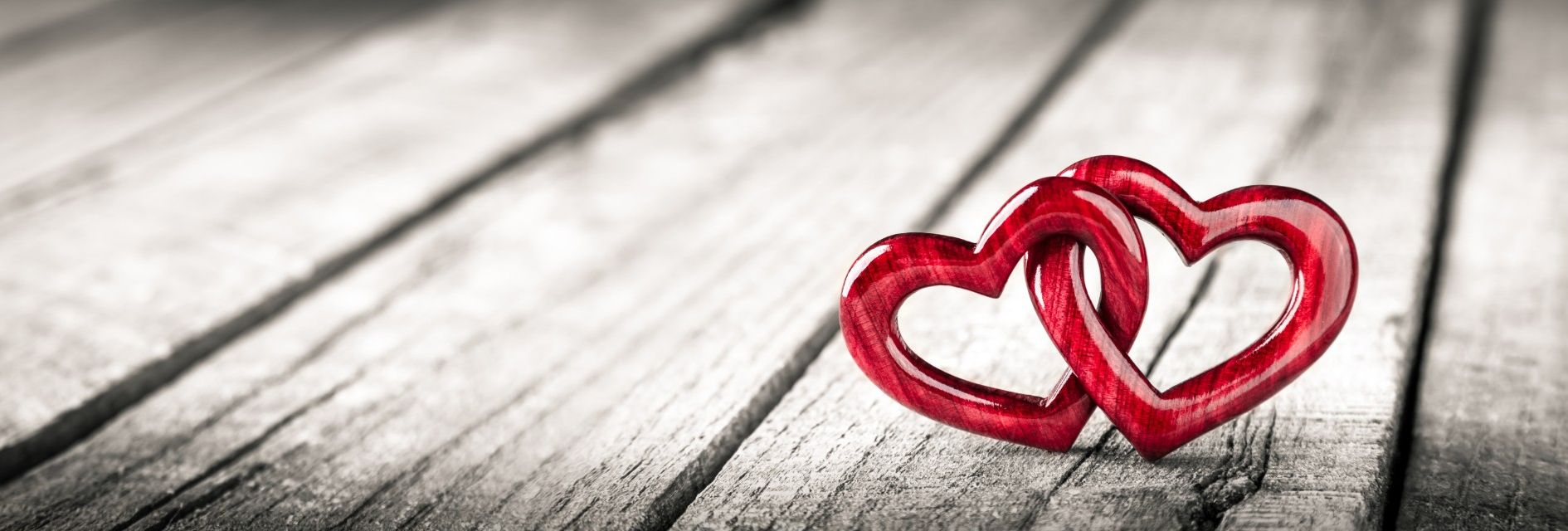 Two red intertwined heart shapes on a wooden surface