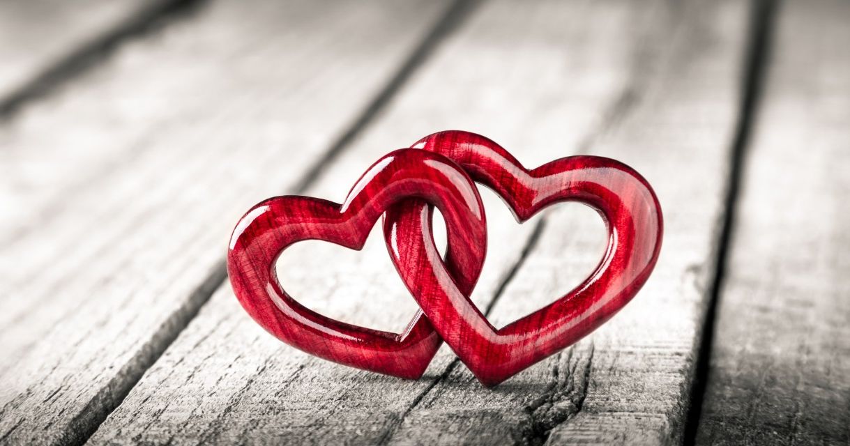 Two red intertwined heart shapes on a wooden surface