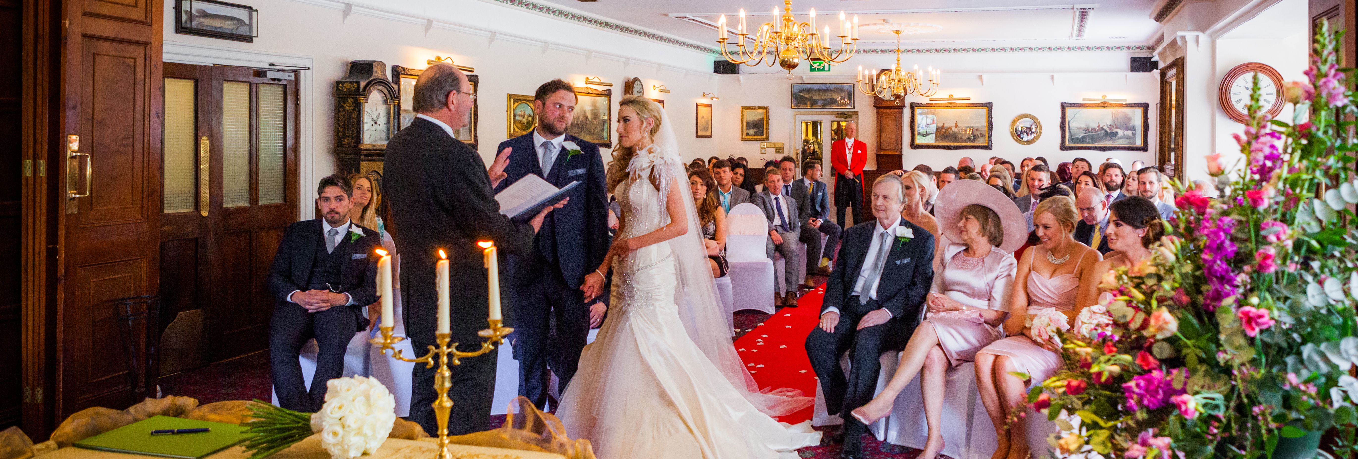 Bride and groom standing at the altar during an indoor wedding ceremony with guests seated and watching.