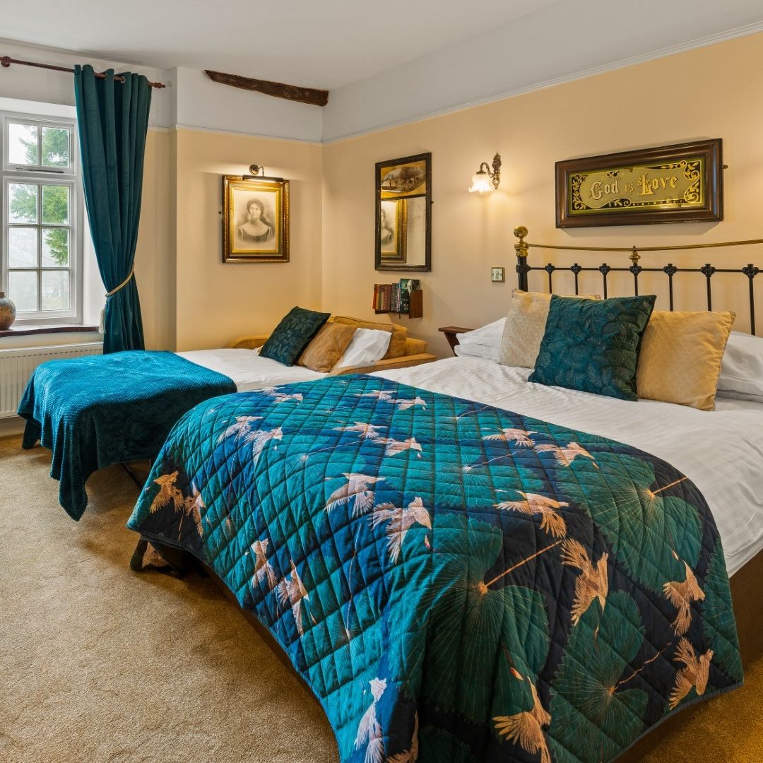 Elegant family hotel room with twin beds, teal bedspreads, and vintage decor