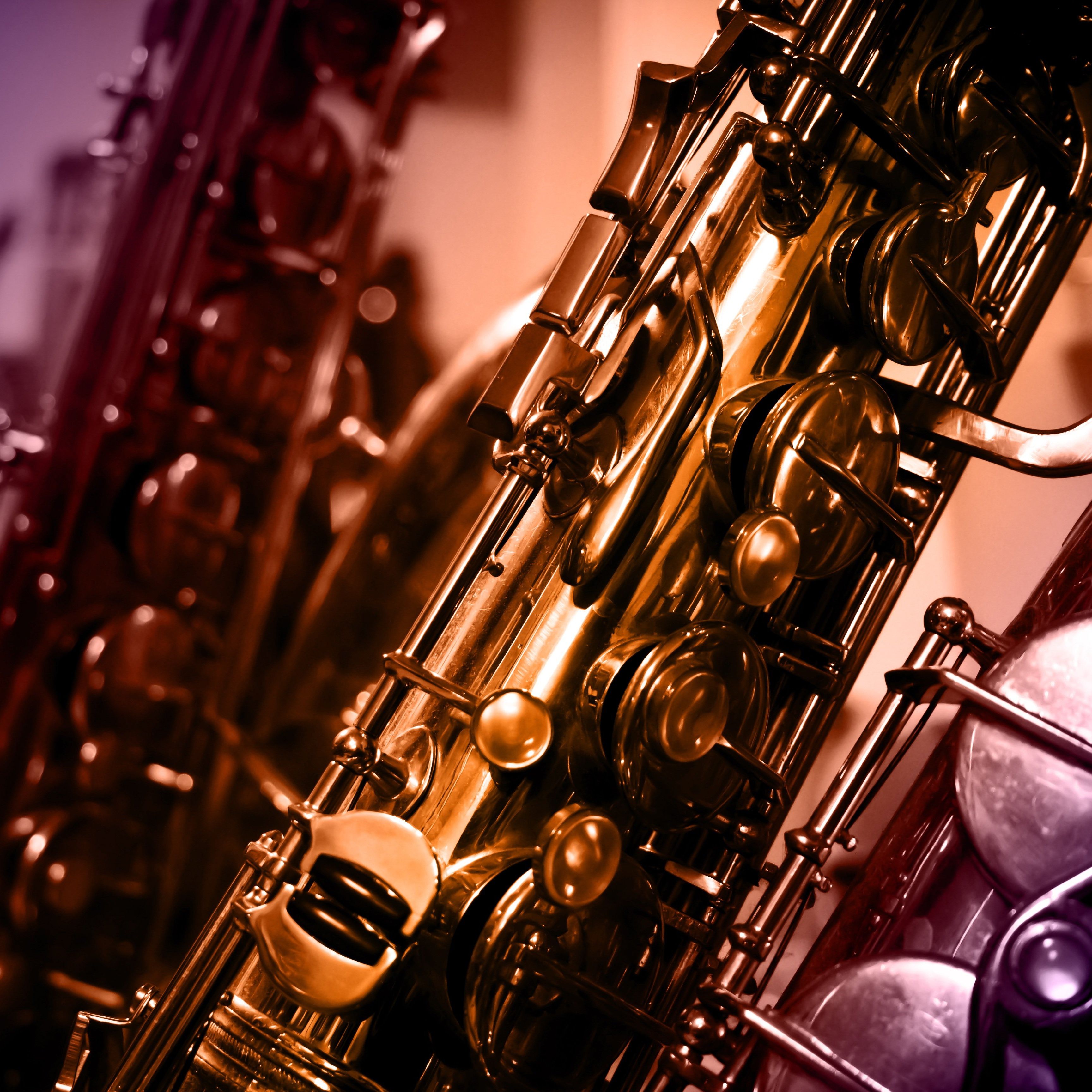 Close-up view of saxophones with blurred musical instruments in the background