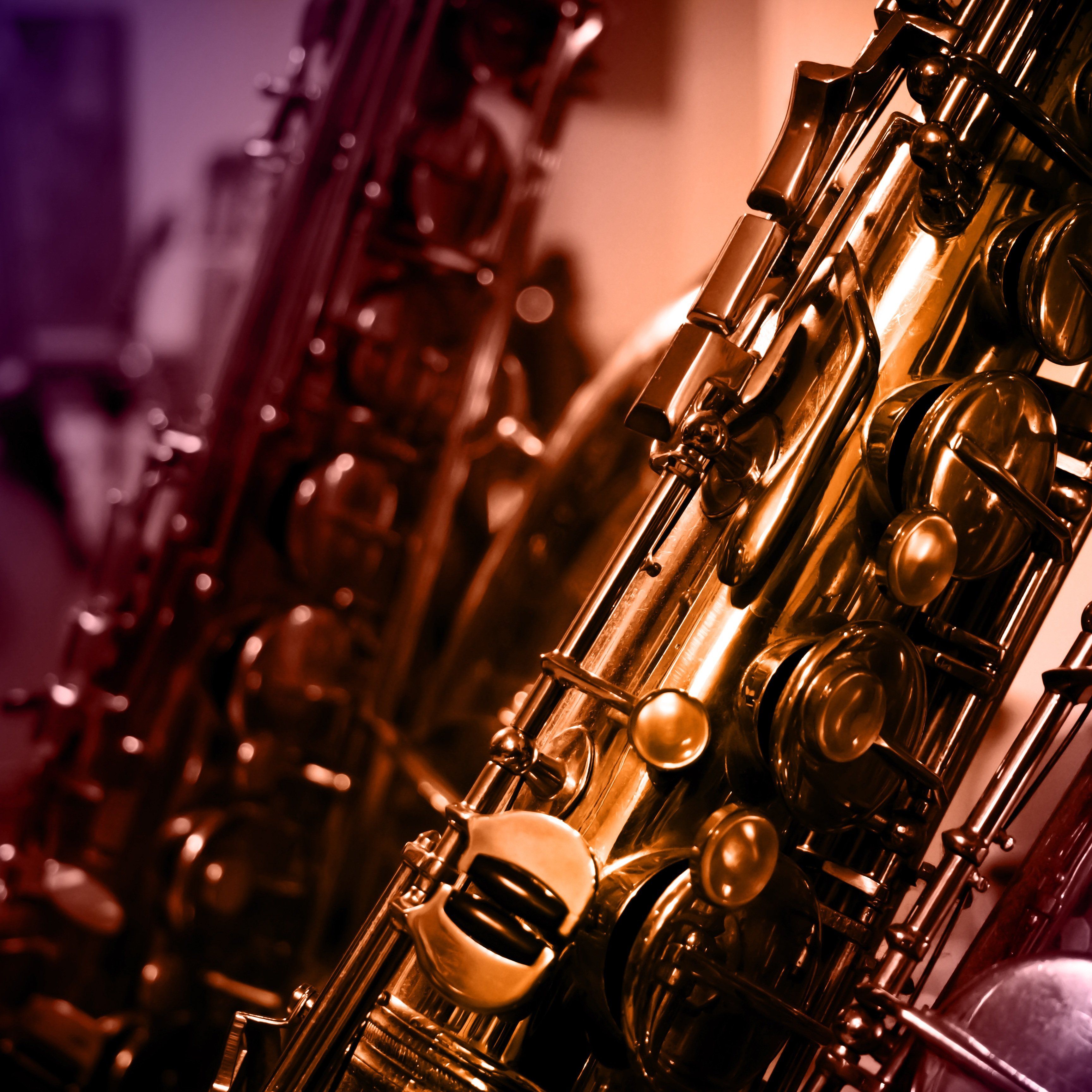 Close-up view of saxophones with blurred musical instruments in the background