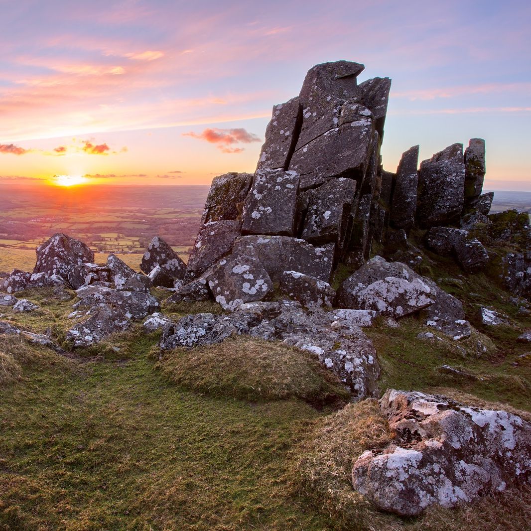 Dartmoor rocky landscape at sunset during autumn, with grassy terrain and dramatic rock formations.