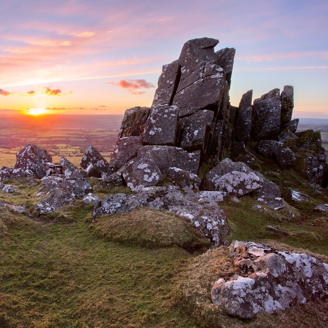 Dartmoor rocky landscape at sunset during autumn, with grassy terrain and dramatic rock formations.