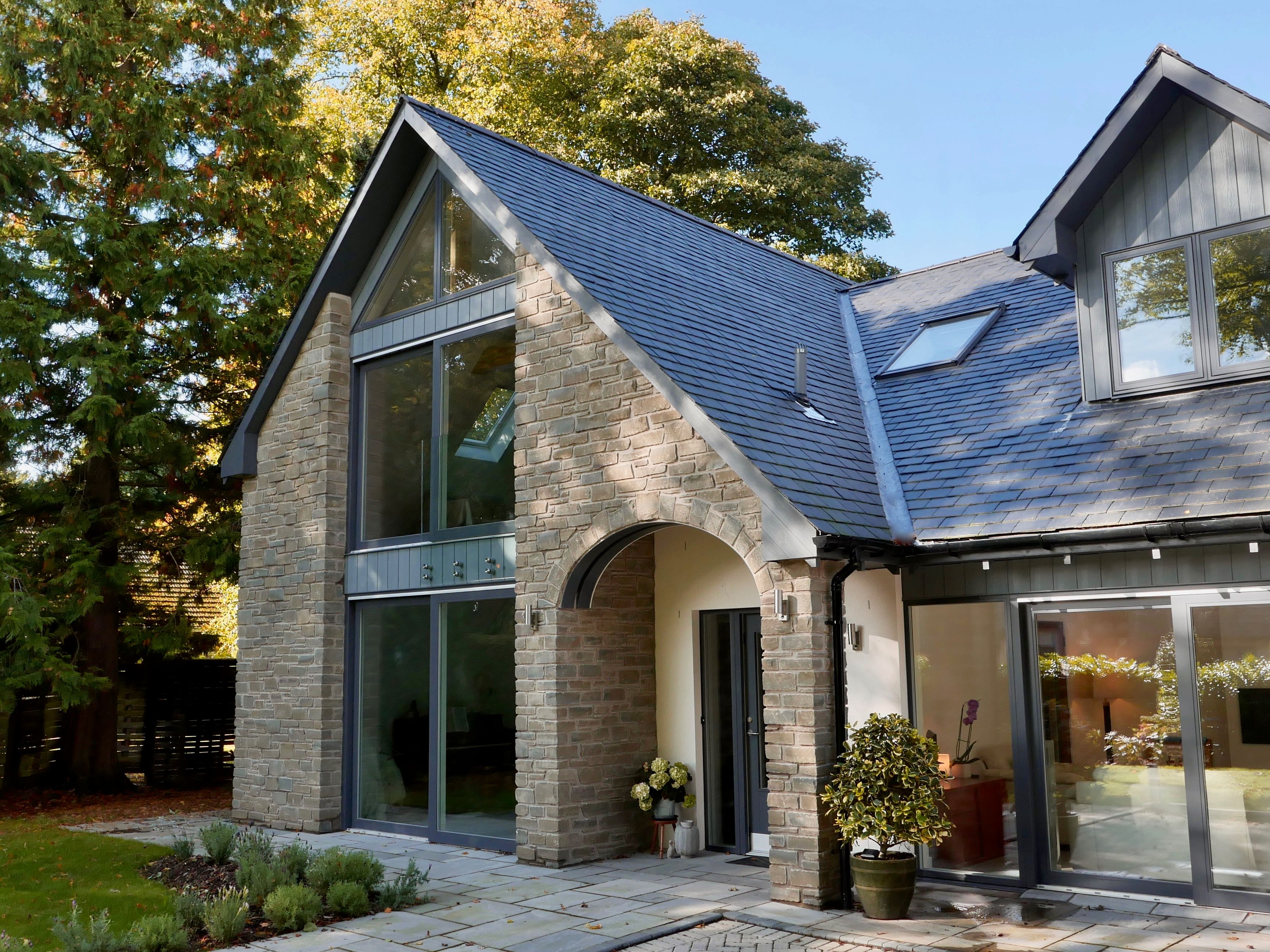 Modern house with stone exterior, large windows, and sloped roof