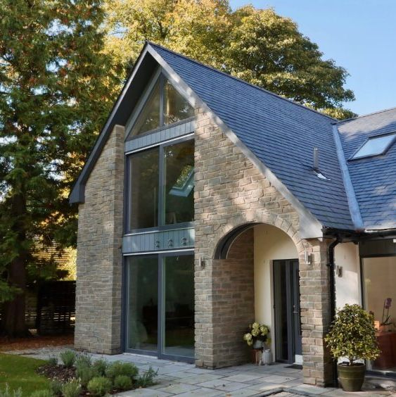 Modern house with large glass windows, stone and slate exterior