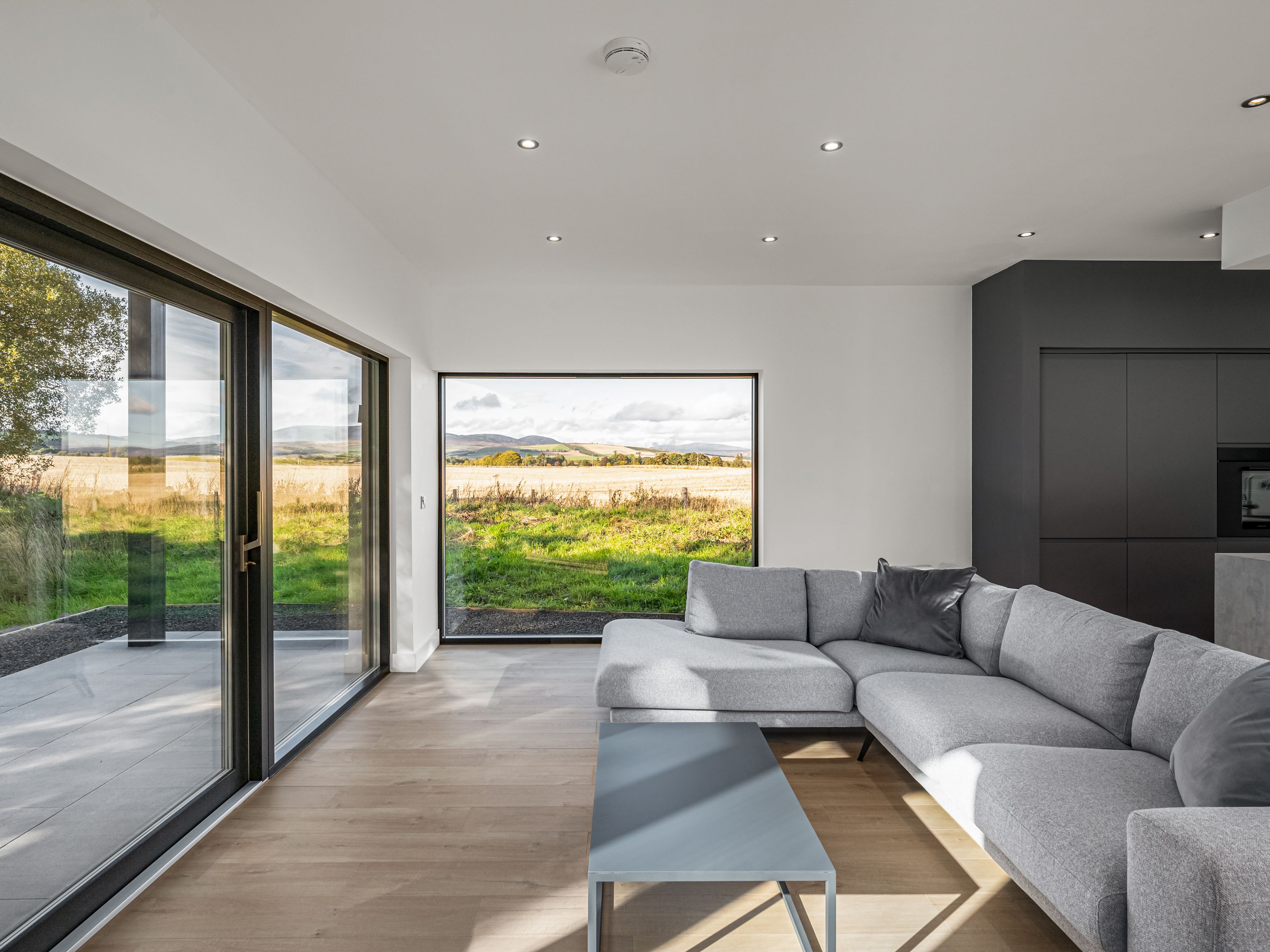 Modern living room with large windows overlooking fields and hills