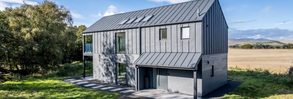 Modern two-story gray house with metal roof in a rural landscape