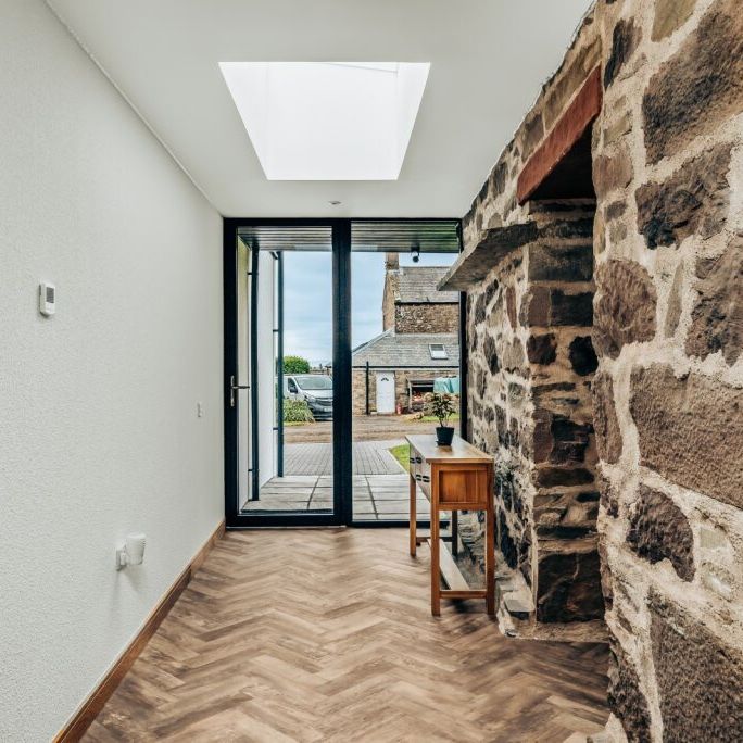 Modern hallway with stone wall, skylight, and glass door