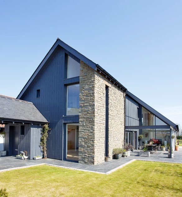 Modern house with stone and dark wood exterior, large windows, and sloped roof