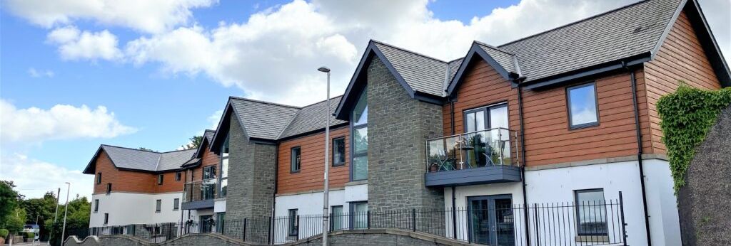 Modern two-story residential buildings with a mix of stone and wood-clad facades along a street.