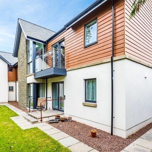 Modern two-story house with wooden and white exterior, glass balcony, and landscaped yard