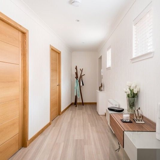 Modern hallway with wooden doors, minimalist decor, and light-colored floors
