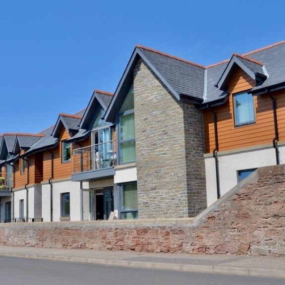 Modern townhouses with brick and wood panel exteriors on a sunny day