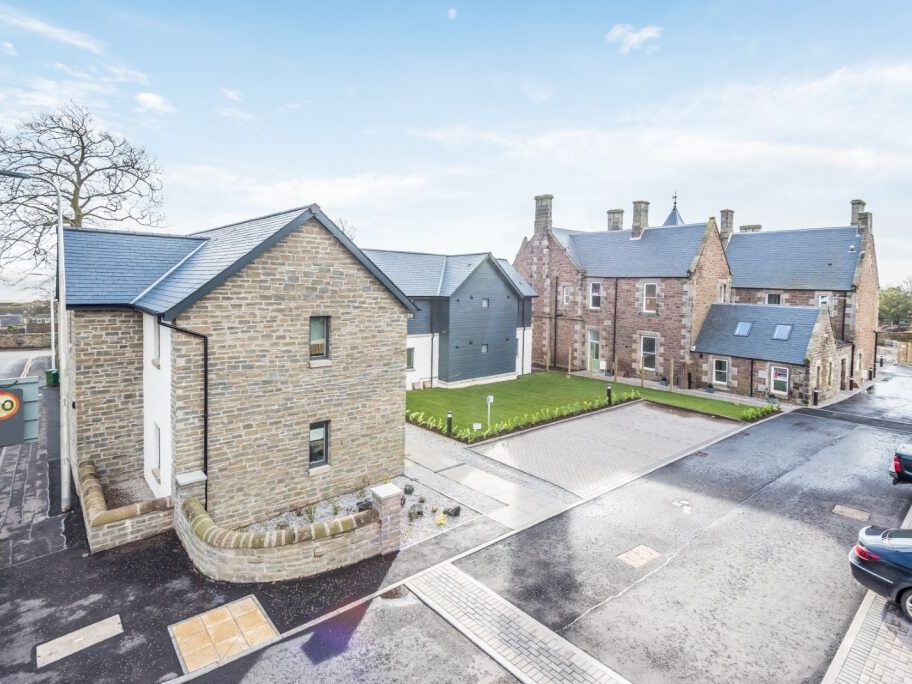 Modern stone buildings with slate roofs and a small green courtyard