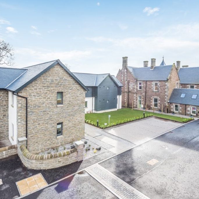 Modern stone buildings with slate roofs and a small green courtyard
