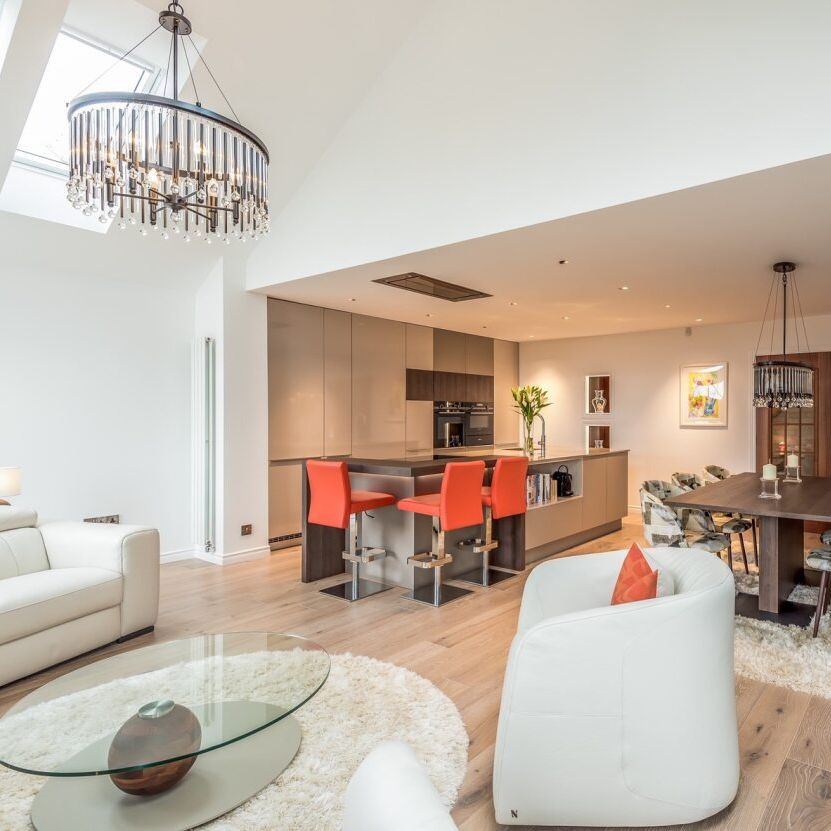 Modern open-plan living area with kitchen, dining, and lounge spaces featuring contemporary furniture and bright accents.