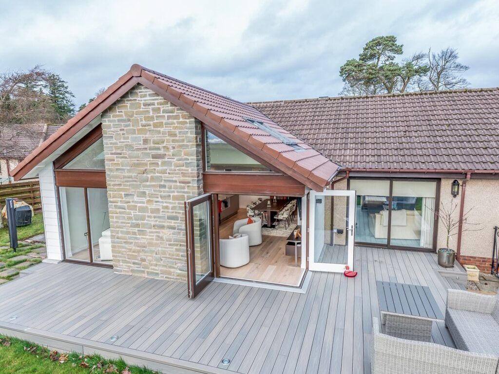 Modern house with large glass doors and a spacious wooden deck.