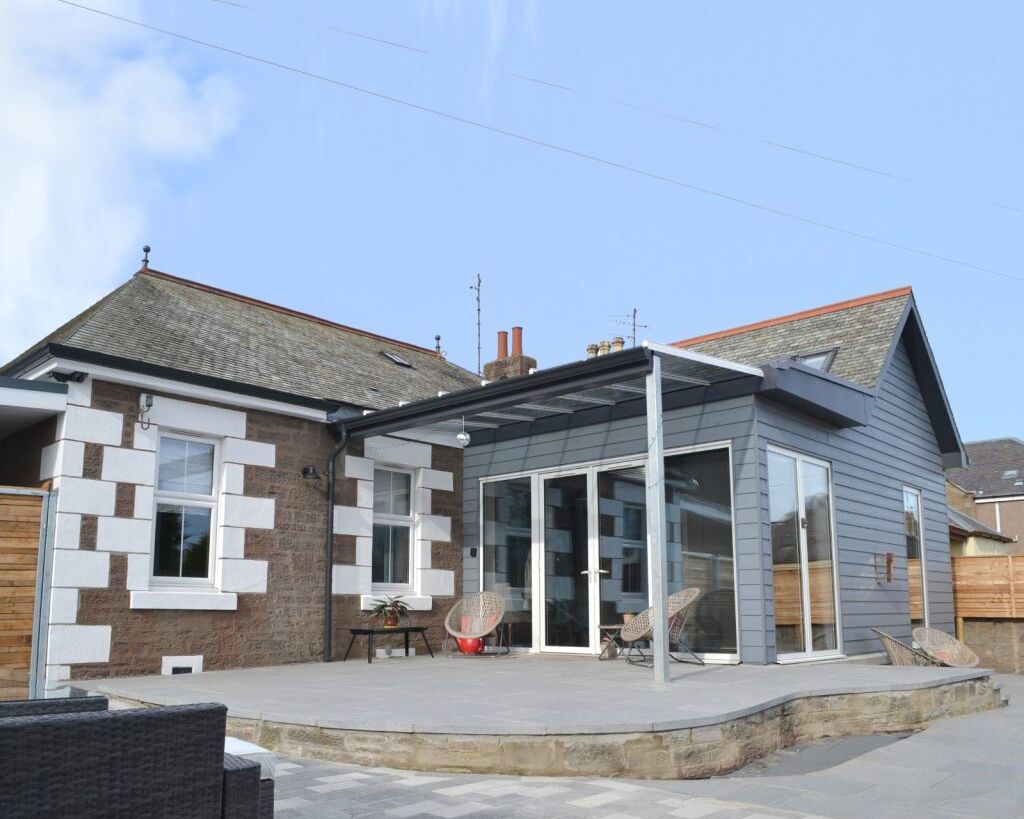 Modern house extension with large glass doors and a patio area.