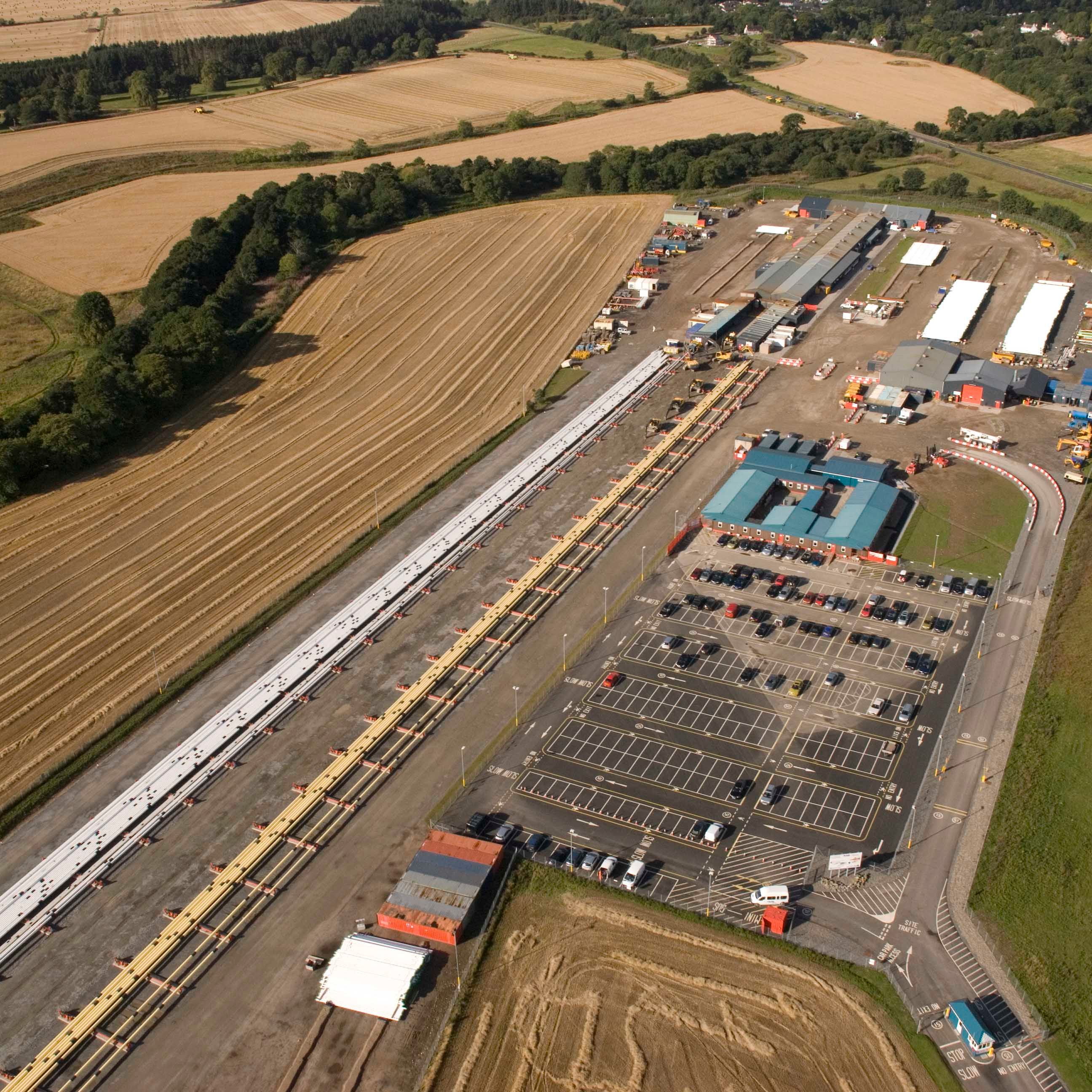 Aerial view of an industrial facility with large parking lots and adjacent farmland.