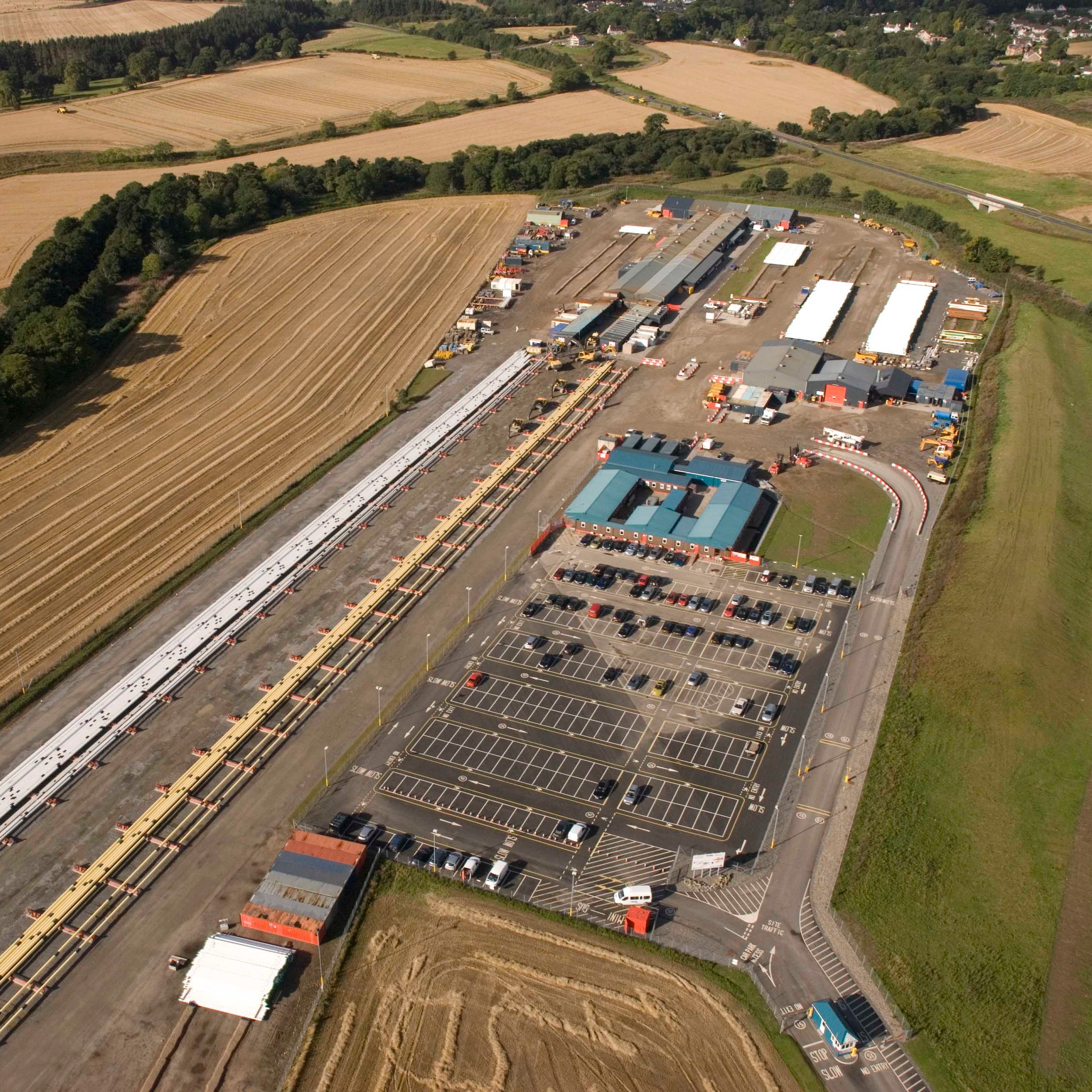 Aerial view of an industrial facility with large parking lots and adjacent farmland.