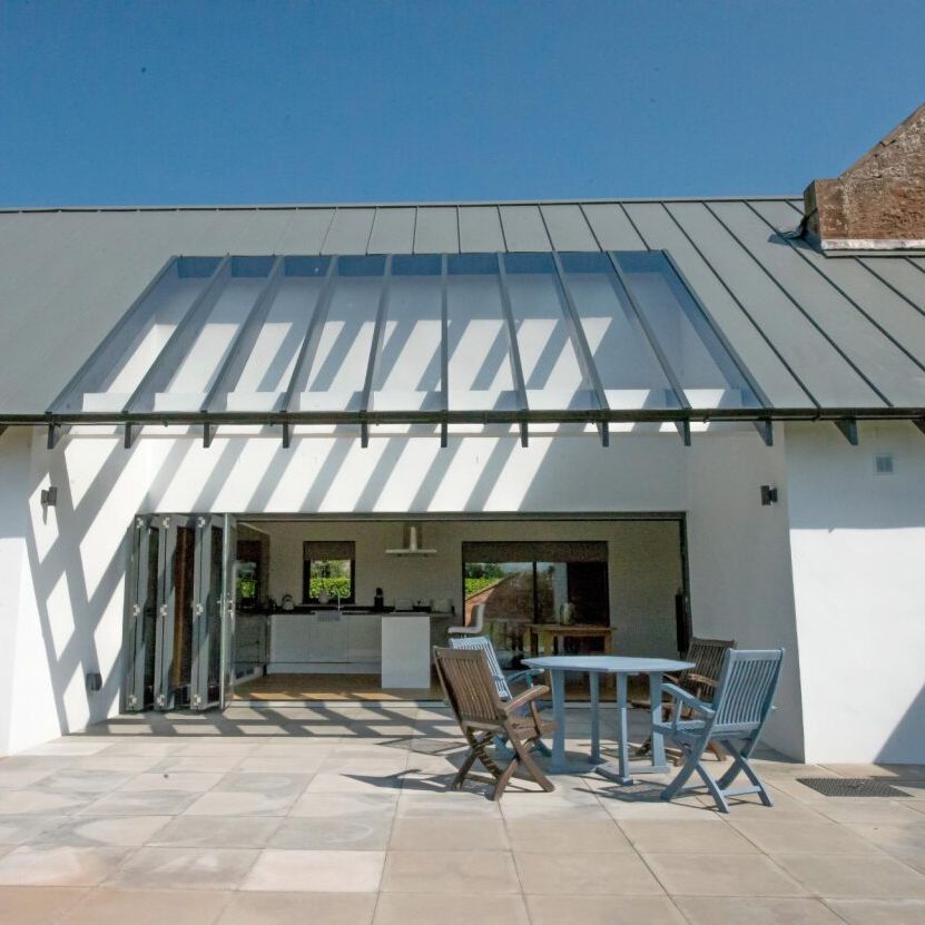 Modern patio with outdoor furniture and open glass doors leading to a kitchen