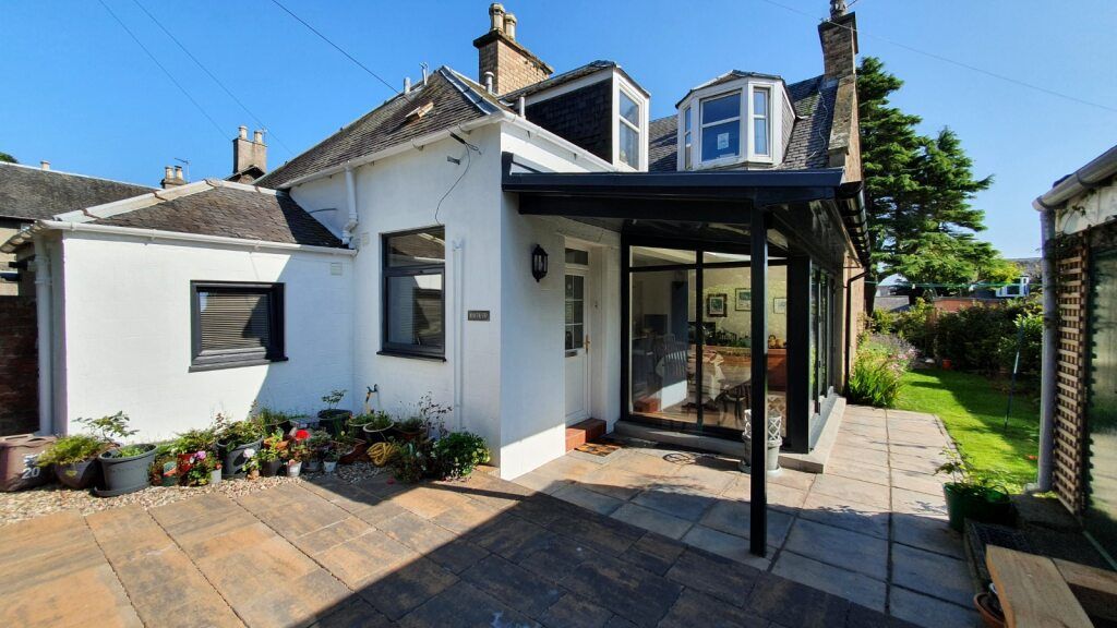 White detached house with modern glass extension and sunny patio area