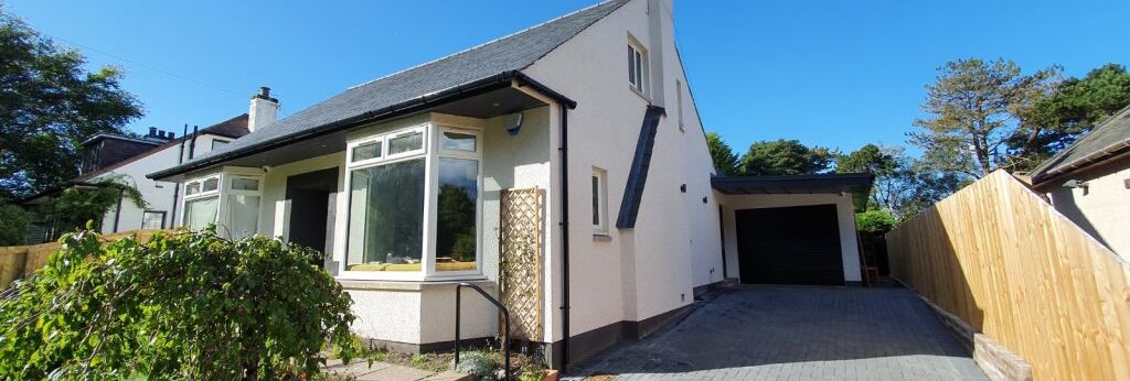 Detached house with driveway and garage under a clear blue sky