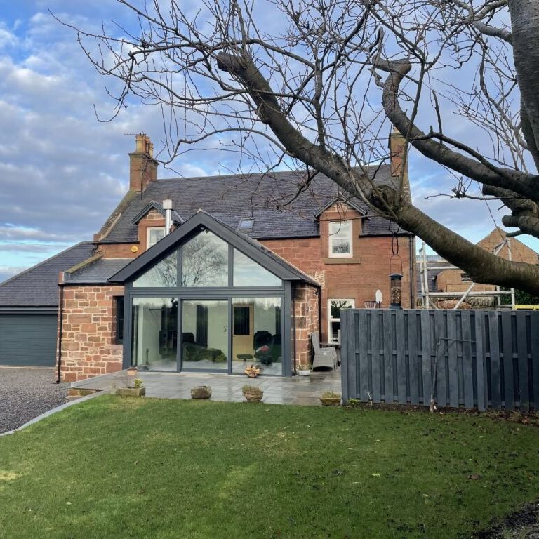 Traditional stone house with modern glass extension and a large garden
