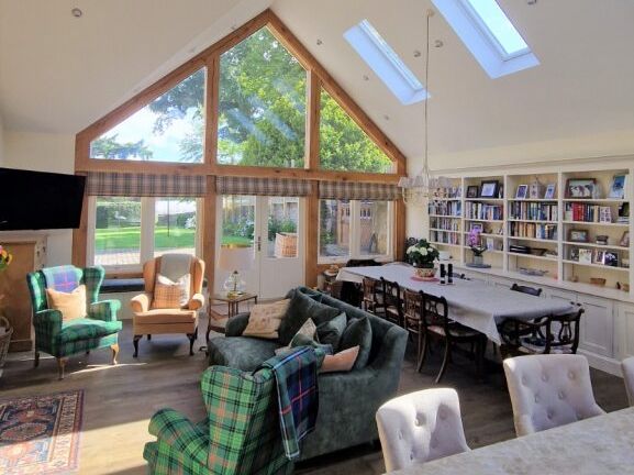 Spacious living and dining area with large windows, skylights, and a mix of classic and modern furniture.