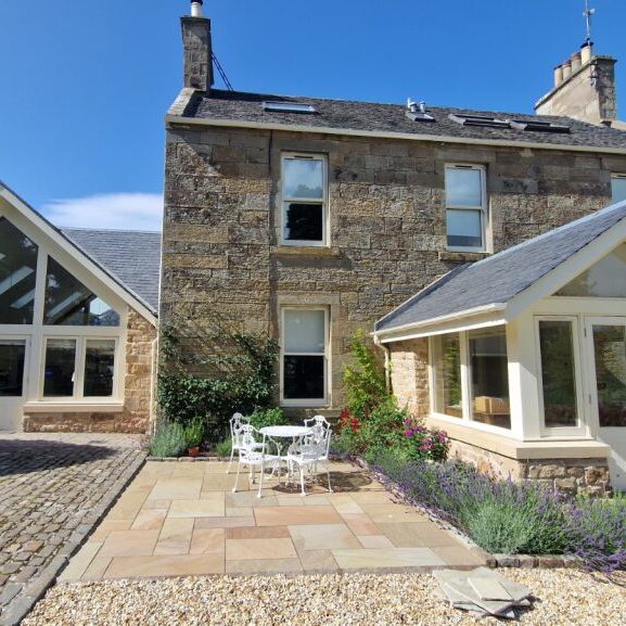 Stone house with modern glass extensions and garden patio