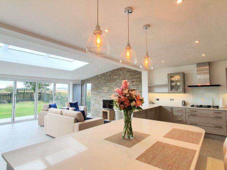 Modern open-plan kitchen and living space with large windows overlooking a garden.