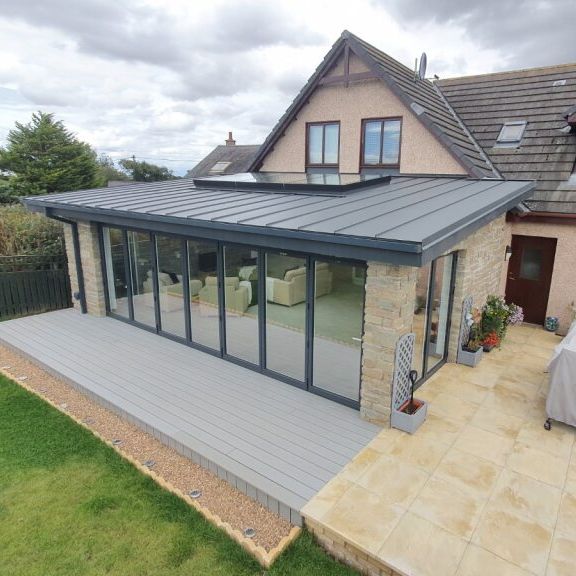 Modern home extension with large glass doors and grey roof.