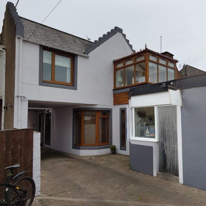 Modern attached house with grey exterior, large windows, and a driveway