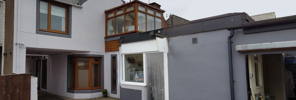 Modern attached house with grey exterior, large windows, and a driveway