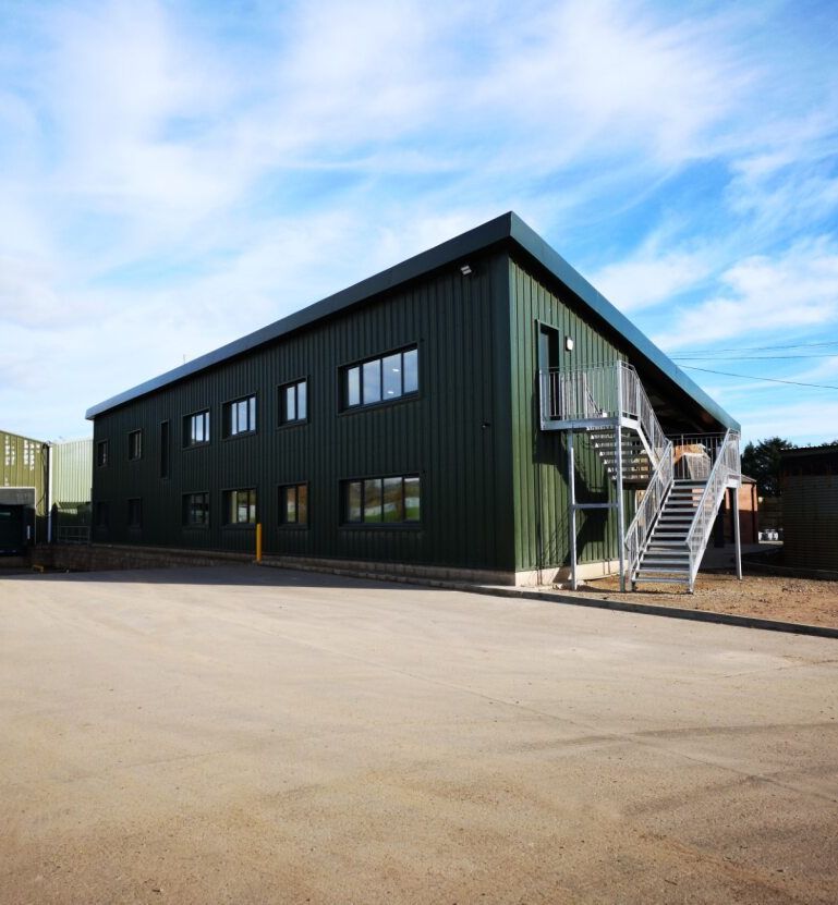 Green metal industrial warehouse building with loading docks and external staircase