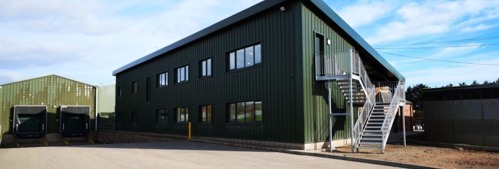 Green metal industrial warehouse building with loading docks and external staircase