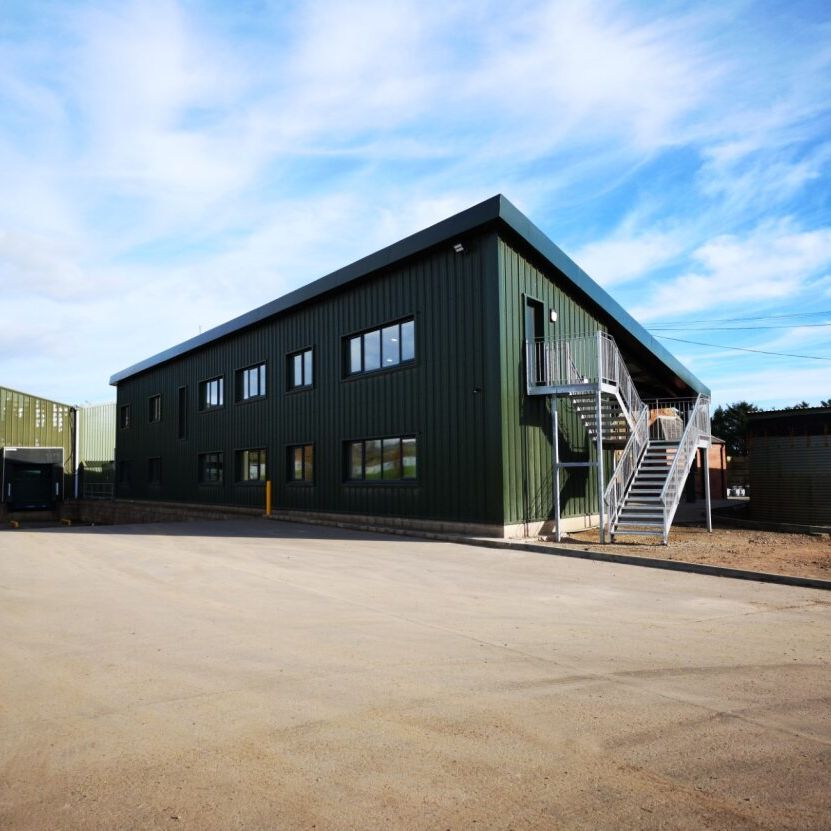 Green metal industrial warehouse building with loading docks and external staircase