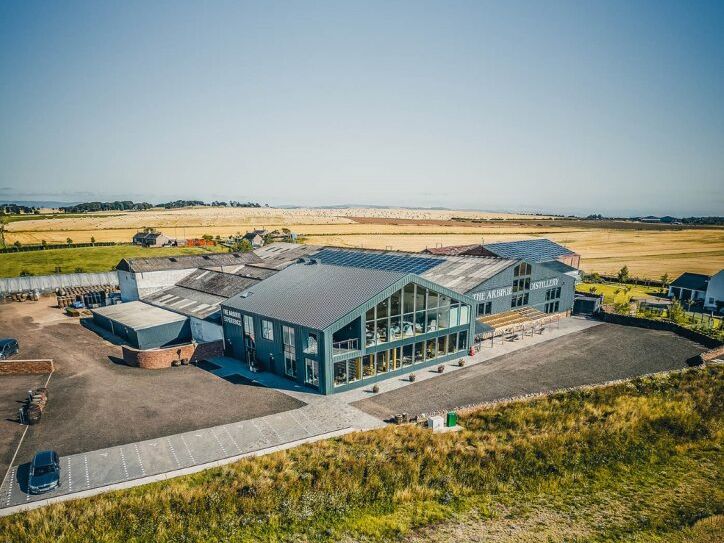 Aerial view of a modern distillery building amidst open countryside