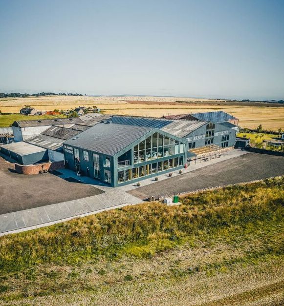 Aerial view of a modern distillery building amidst open countryside