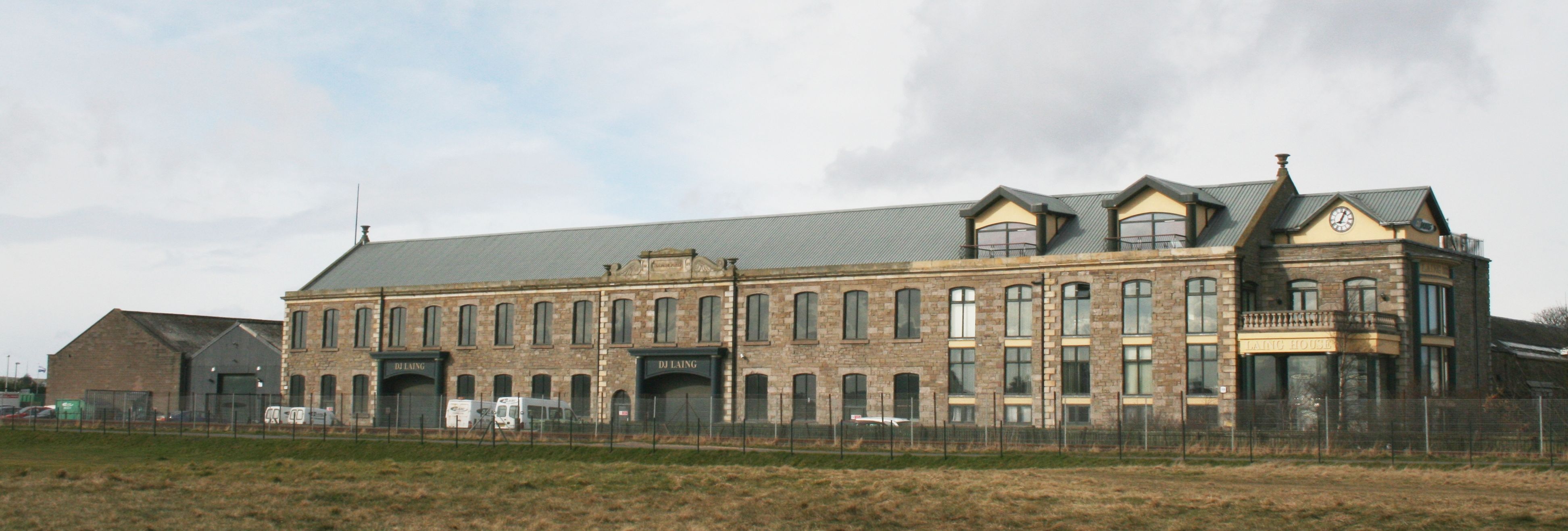 Large historic stone building with multiple arched windows and a clock on the corner