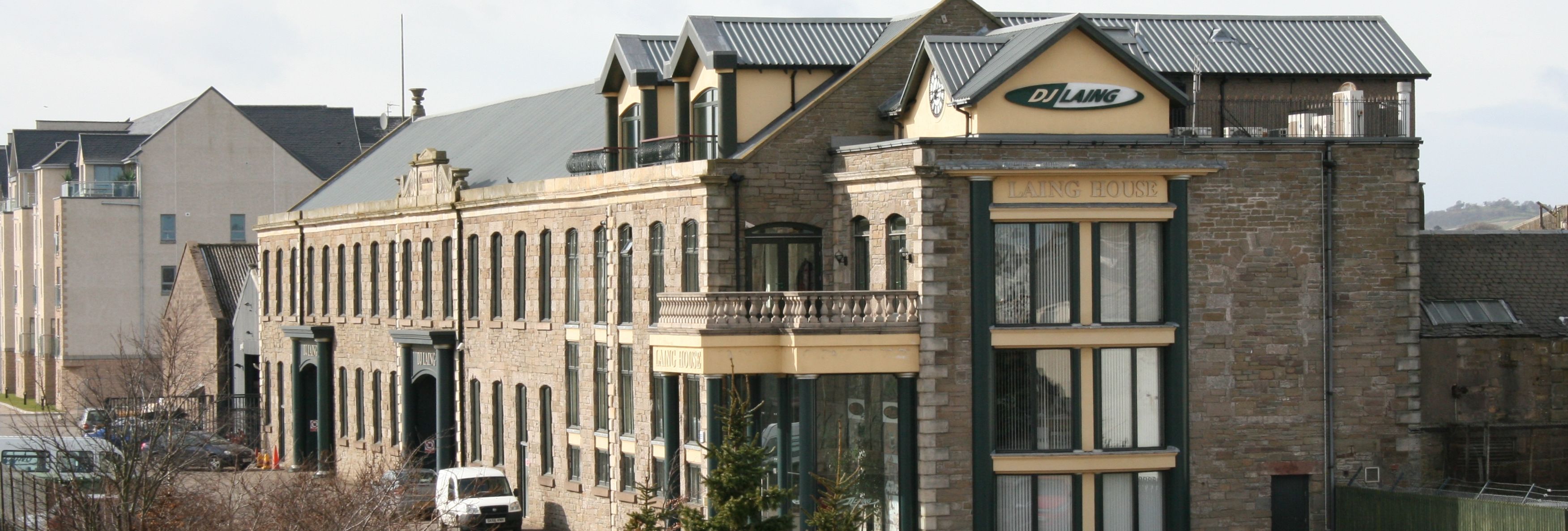 Stone office building with sign 'DJ Laing' and several parked cars in front.