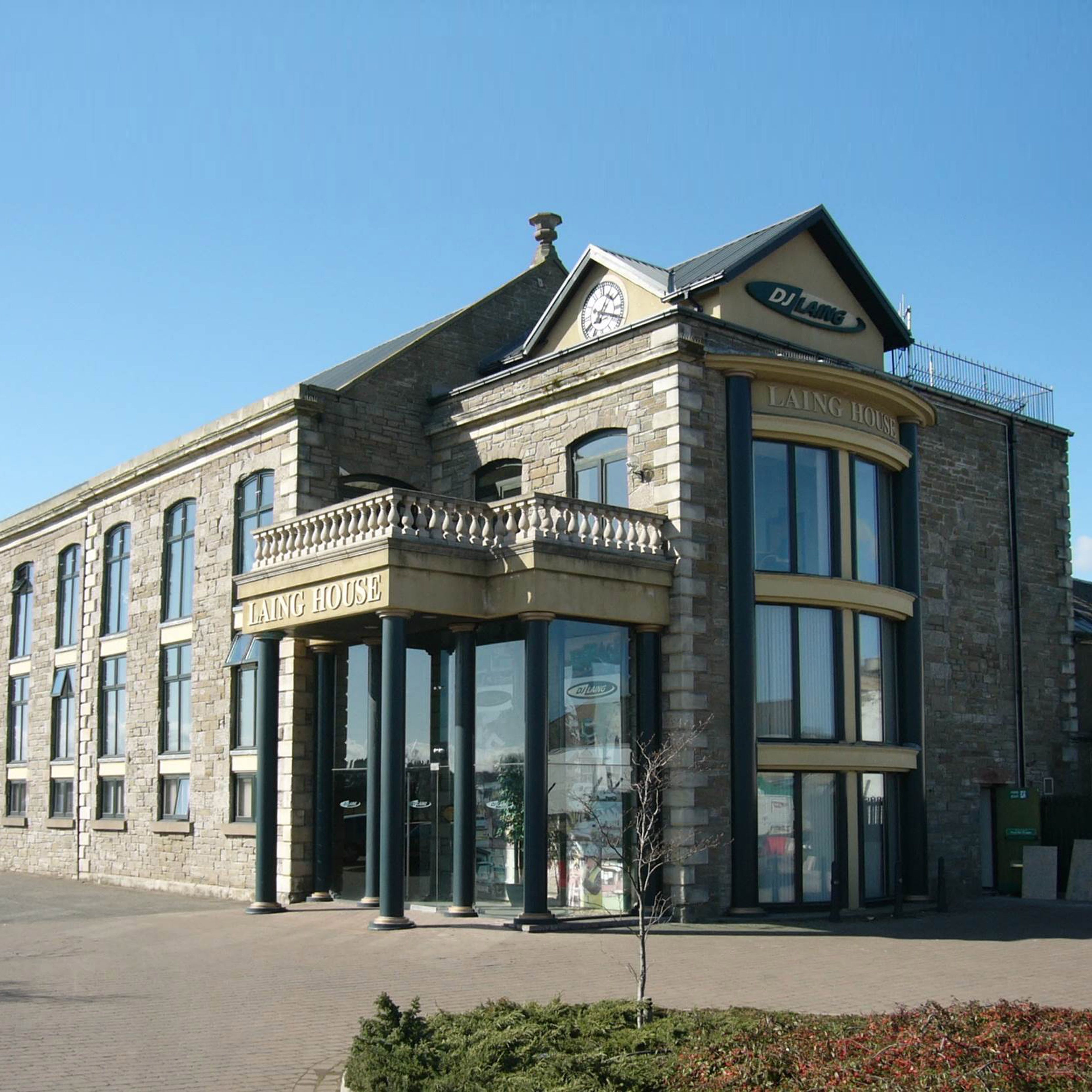 Stone commercial building with large glass windows and a sign reading 'Laing House'